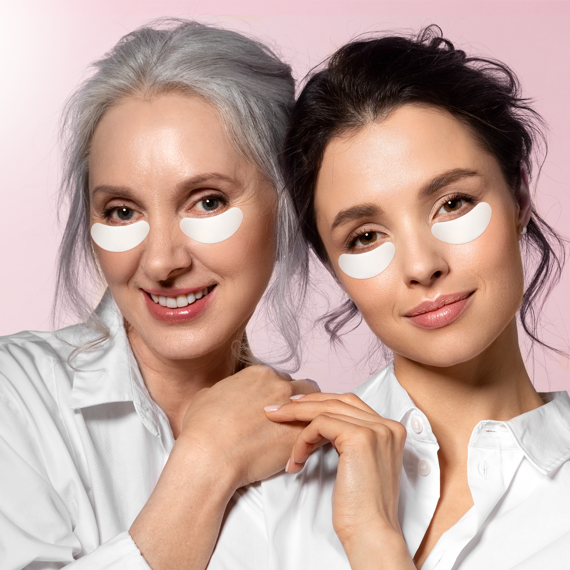 Two women with under-eye patches on a pink background